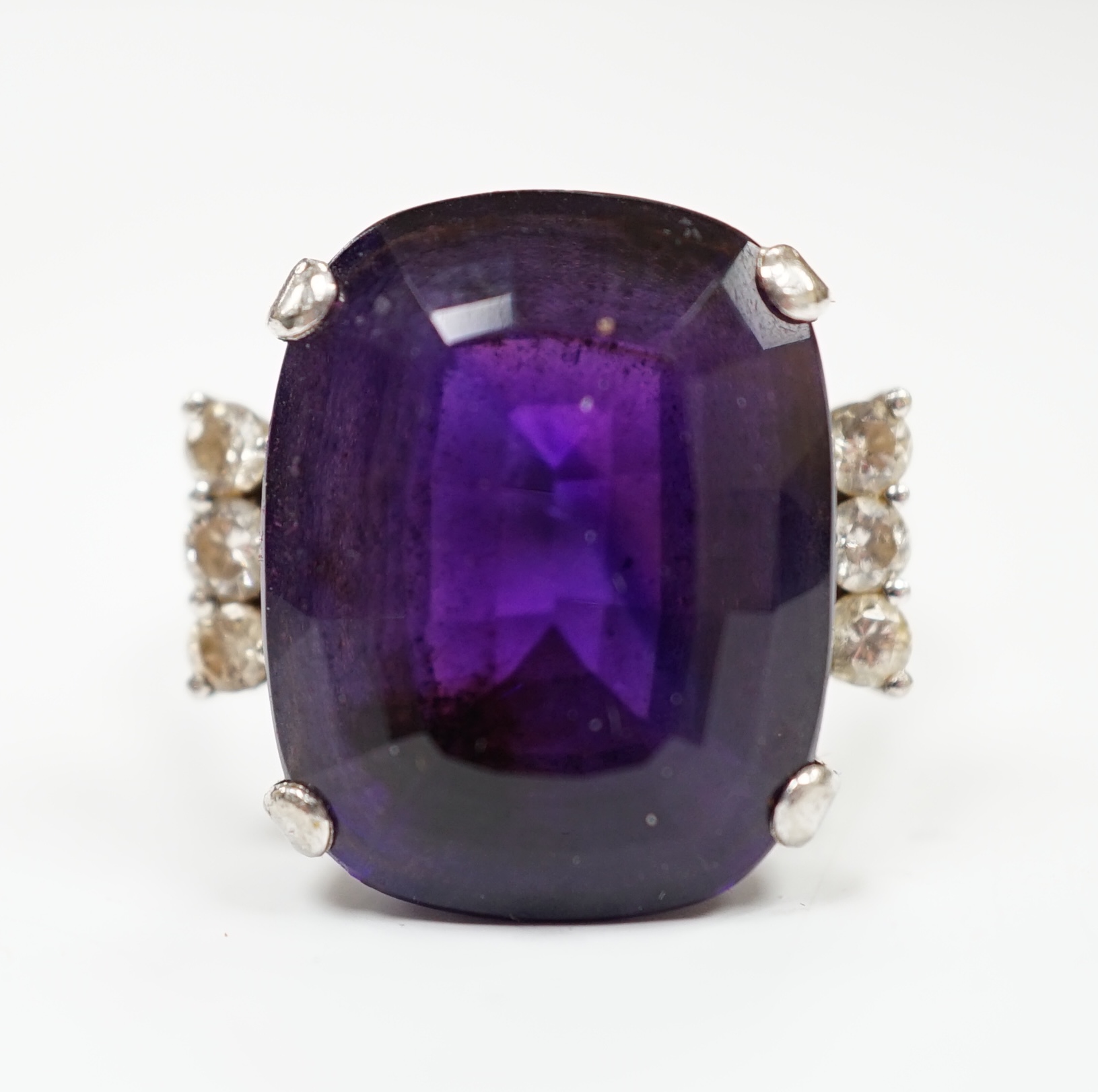 A white metal and single stone cushion cut amethyst set dress ring, with six stone diamond set shoulders, size O, gross weight 9.2 grams.